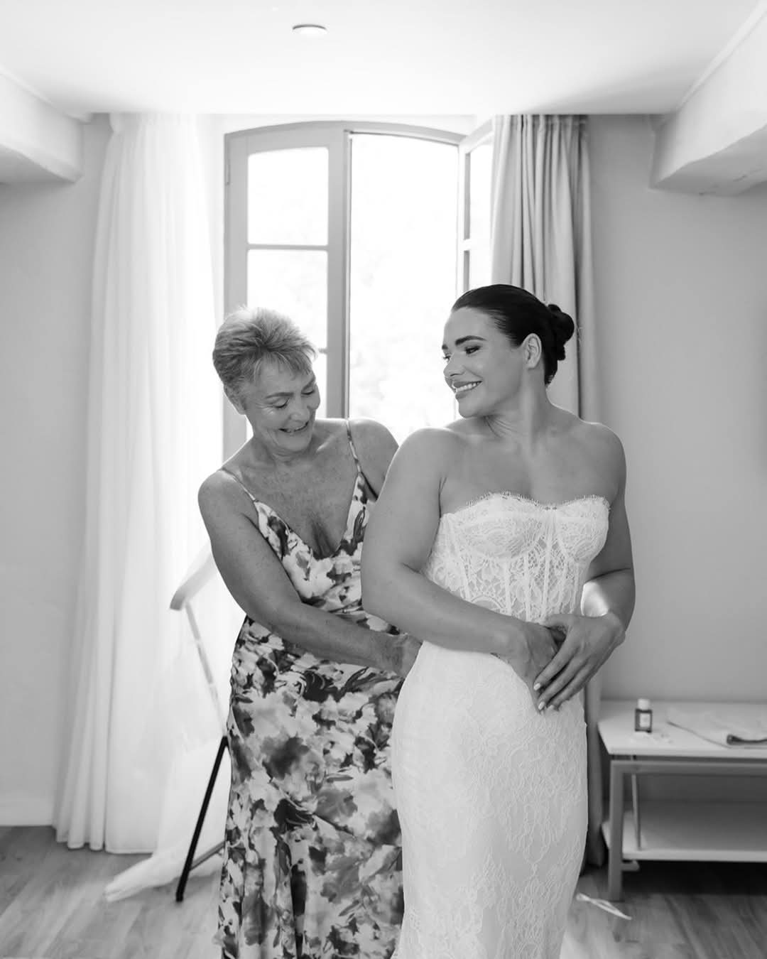 Bride getting ready with her mother by the window