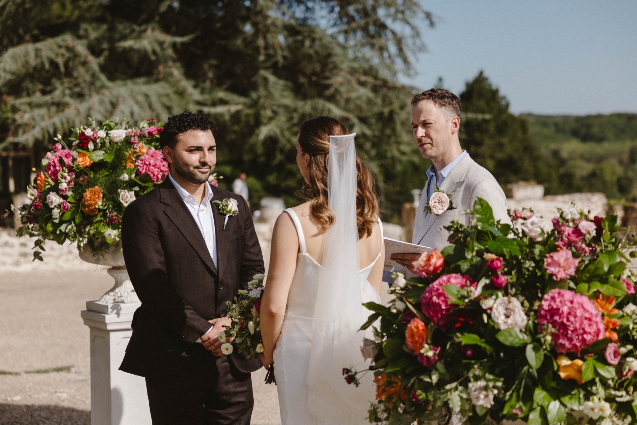 Groom waiting at the ceremony beside bright floral arrangements