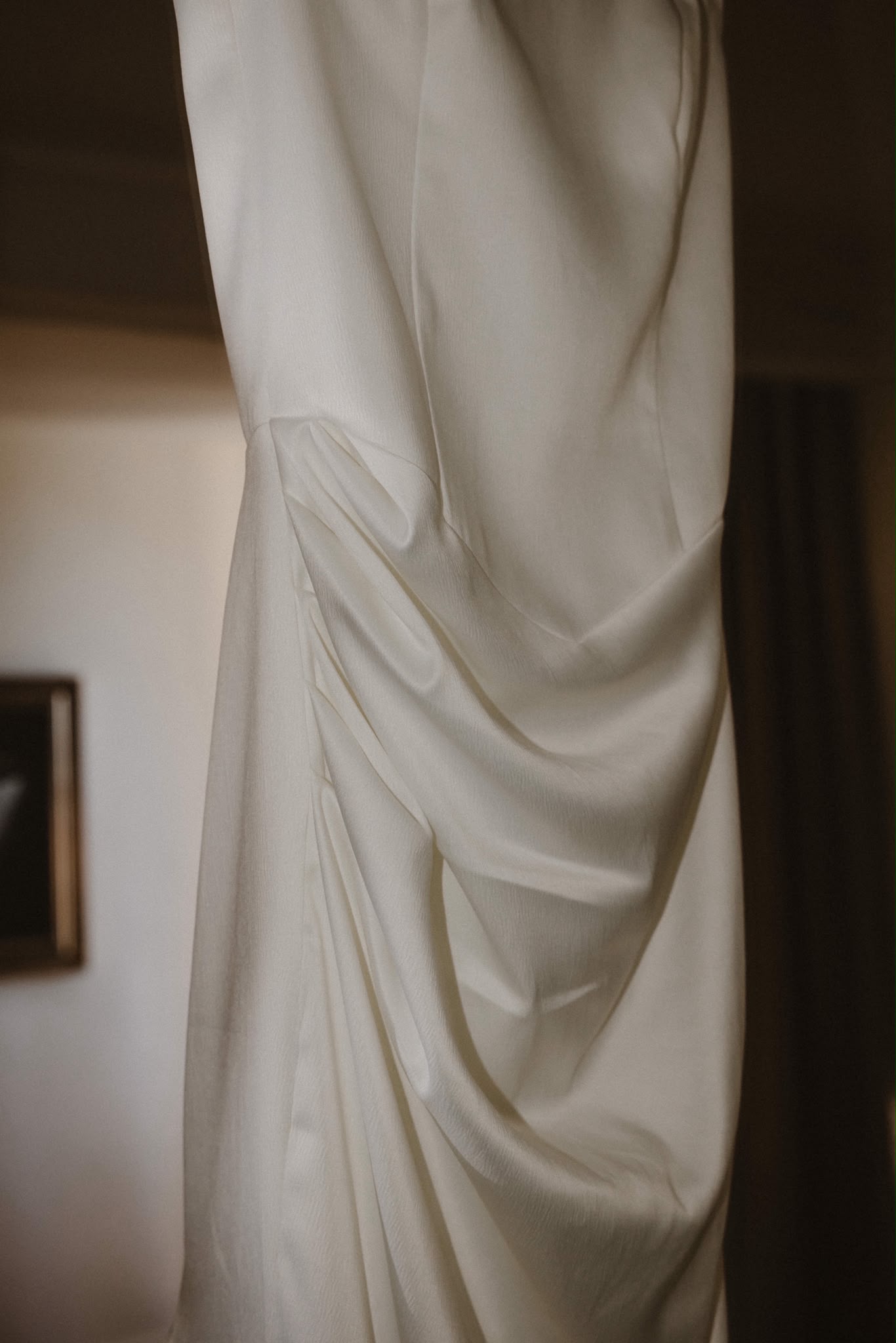 Bridal gown draped by a window