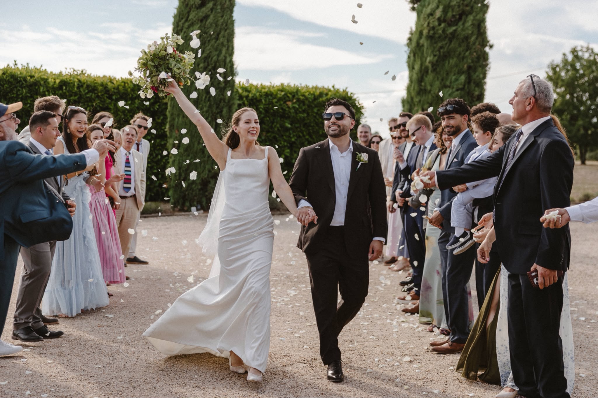 Newlyweds walking back down the aisle as guests throw petals