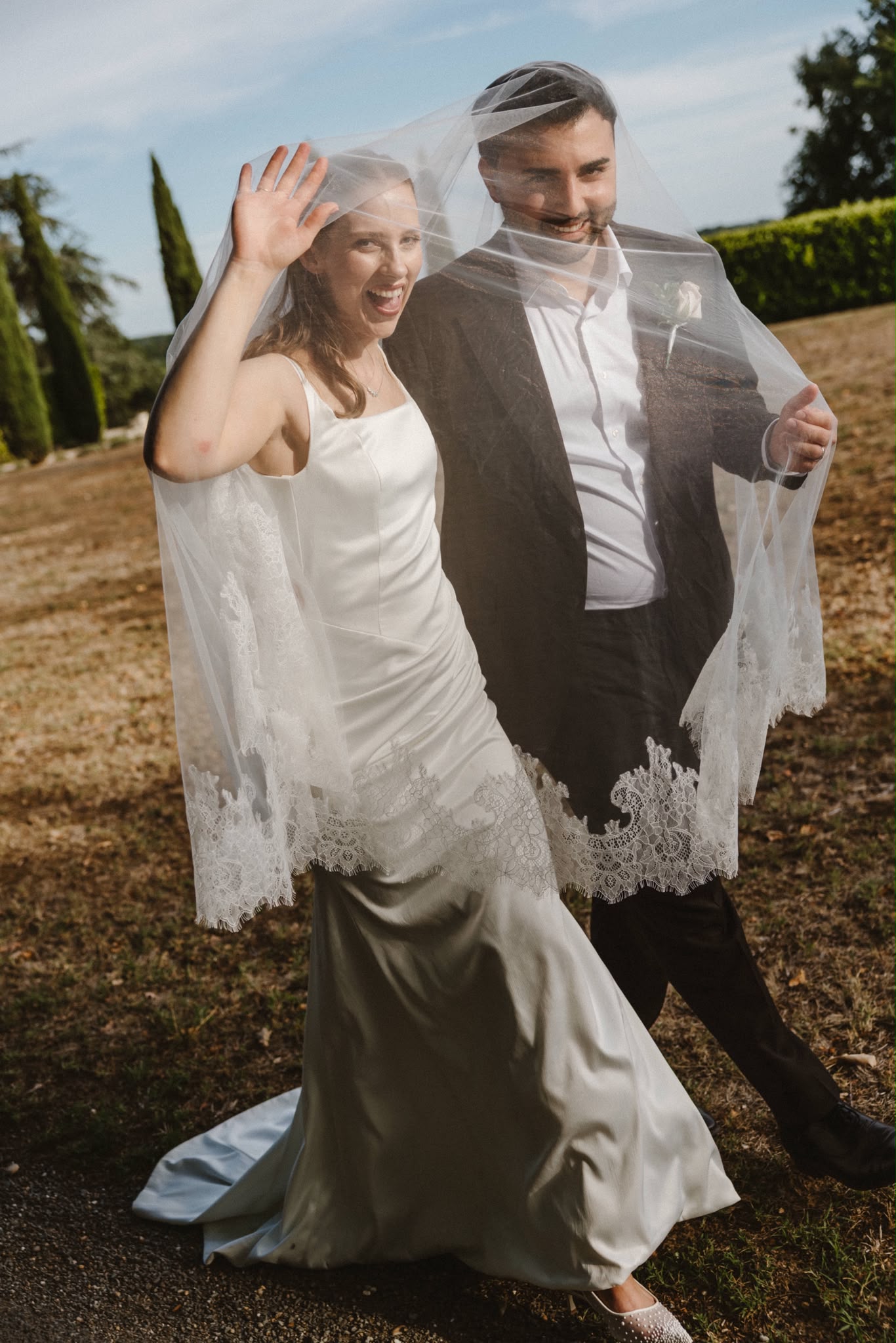 Couple celebrating, her veil lifted in the breeze