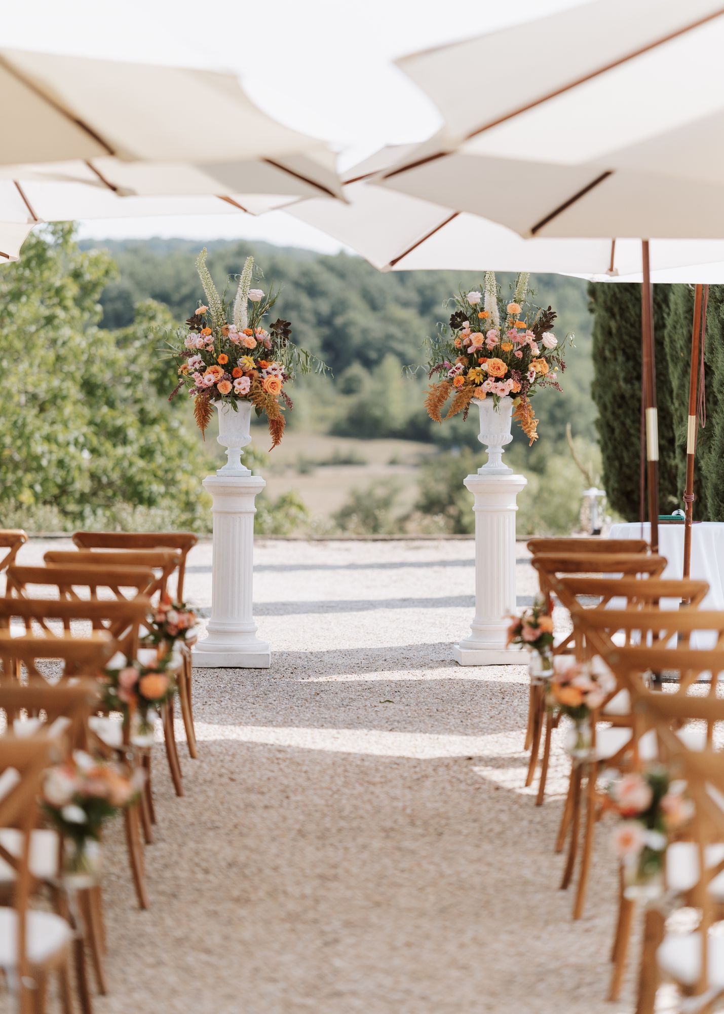 Wedding ceremony aisle with floral urns and parasols